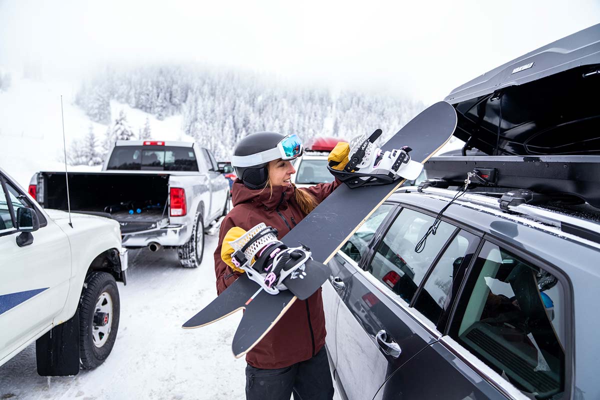 Loading directional Season snowboard into rooftop cargo box