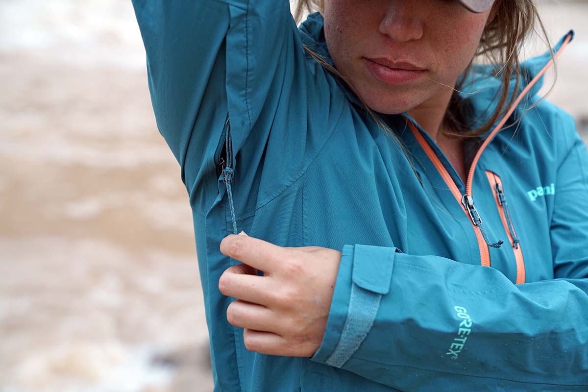 Woman unzipping pit zip of Patagonia Calcite Rain Jacket