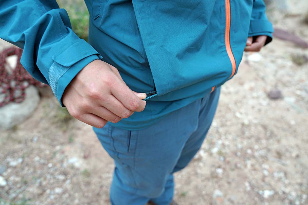 Zipping up handwarmer pocket in Patagnia Calcite rain jacket