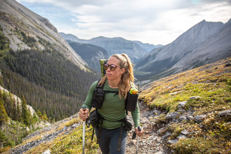 A woman hiking in the mountains in a green baselayer