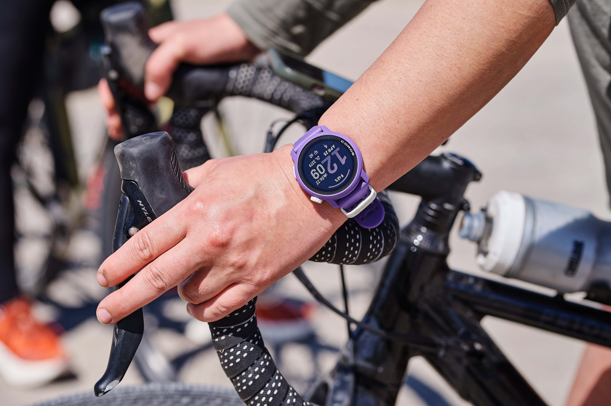 A wrist wearing the Coros Pace 3 fitness watch while pressing the breaks on a bike
