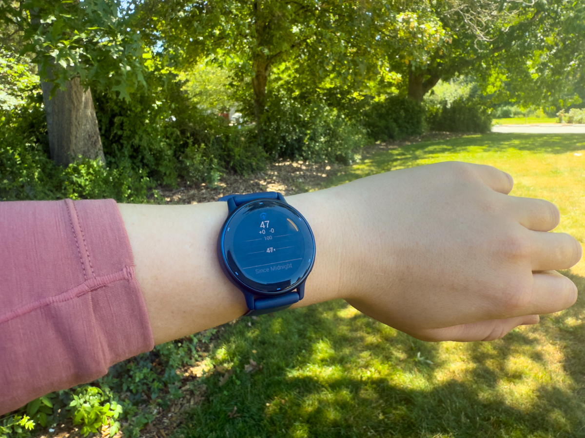 Garmin's vivoactive 5 fitness watch on a wrist in front of trees on a sunny day