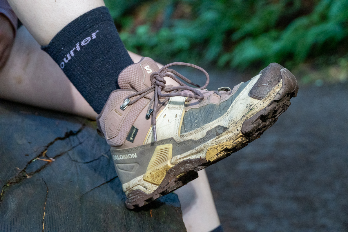 A brown and white hiking boot propped up on a log