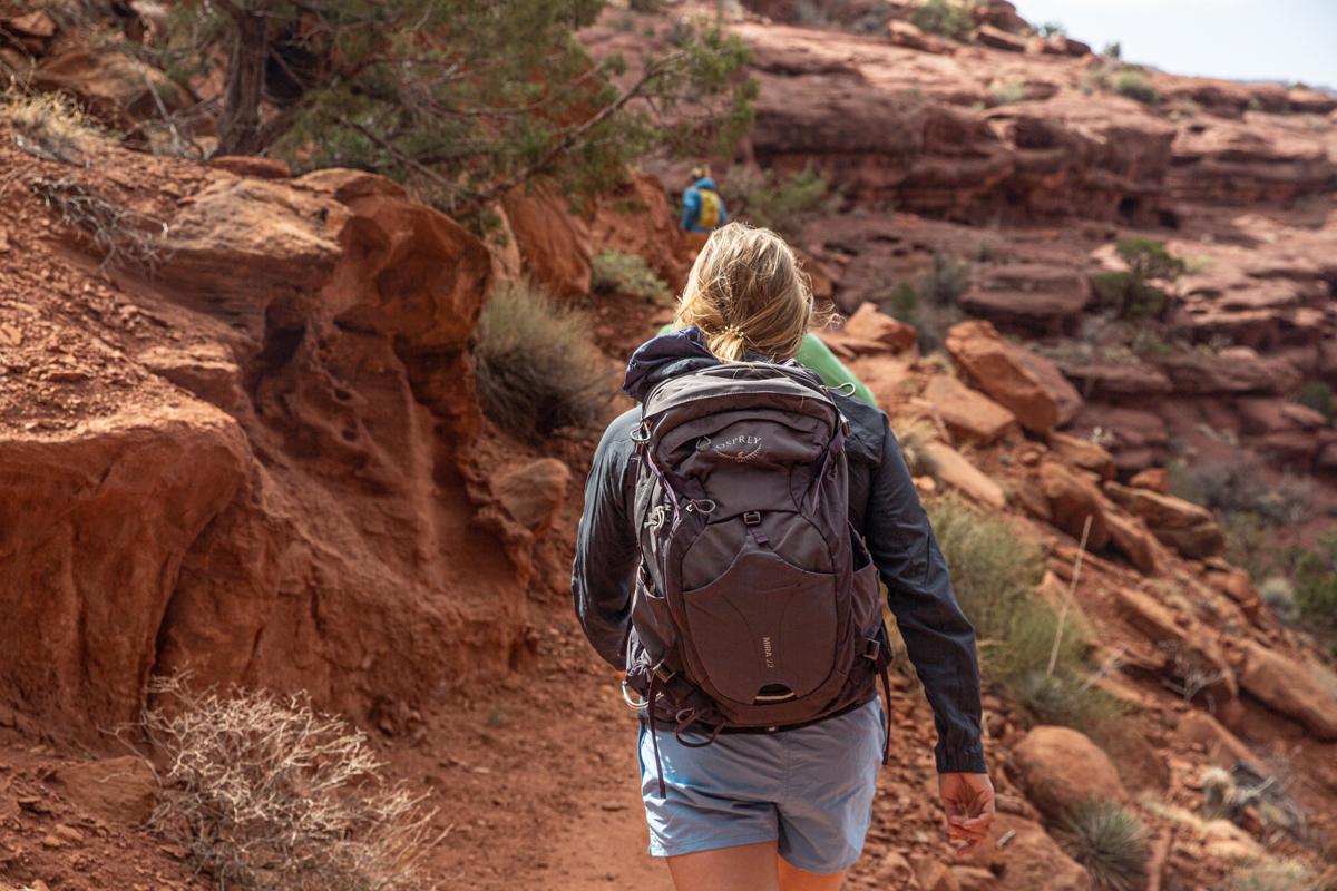A woman hiking in the desert with a brown Osprey hydration pack