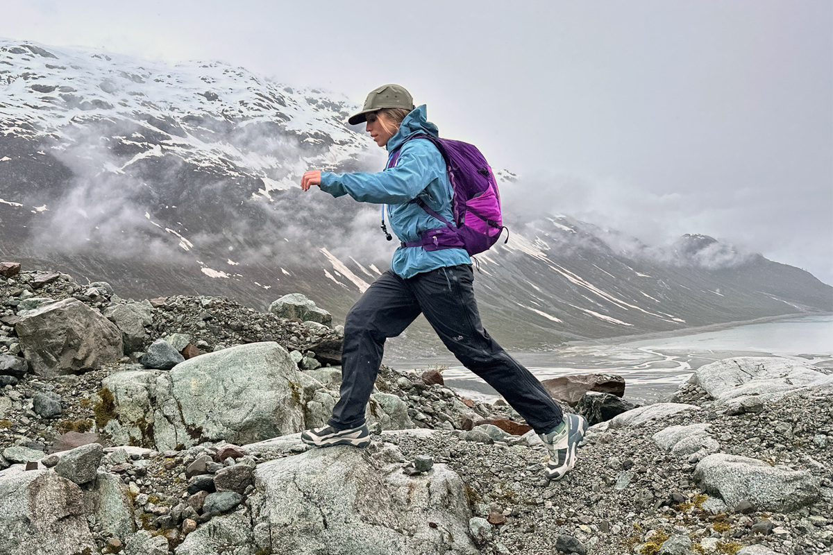 A woman hopping onto a boulder while hiking in a foggy rocky landscape
