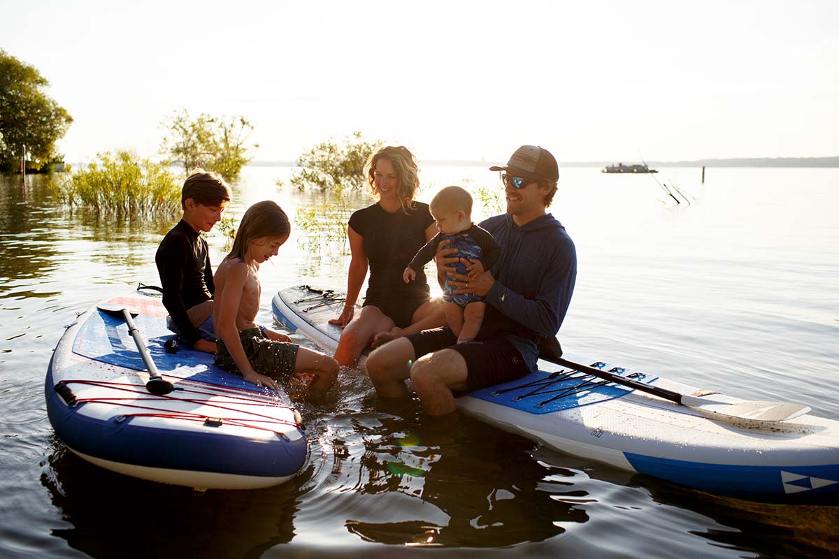 Family with parents and kids and baby on stand-up paddle board (SUP)