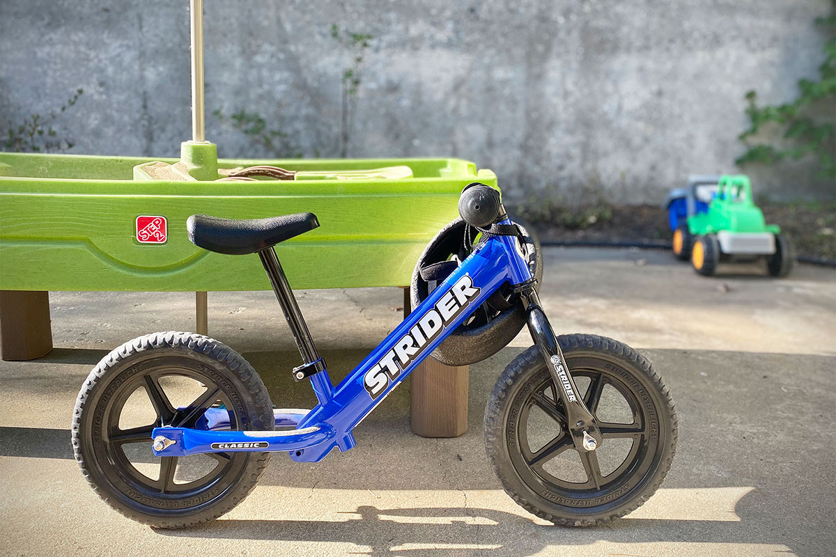 Strider Kids' Balance Bike (leaning against table)