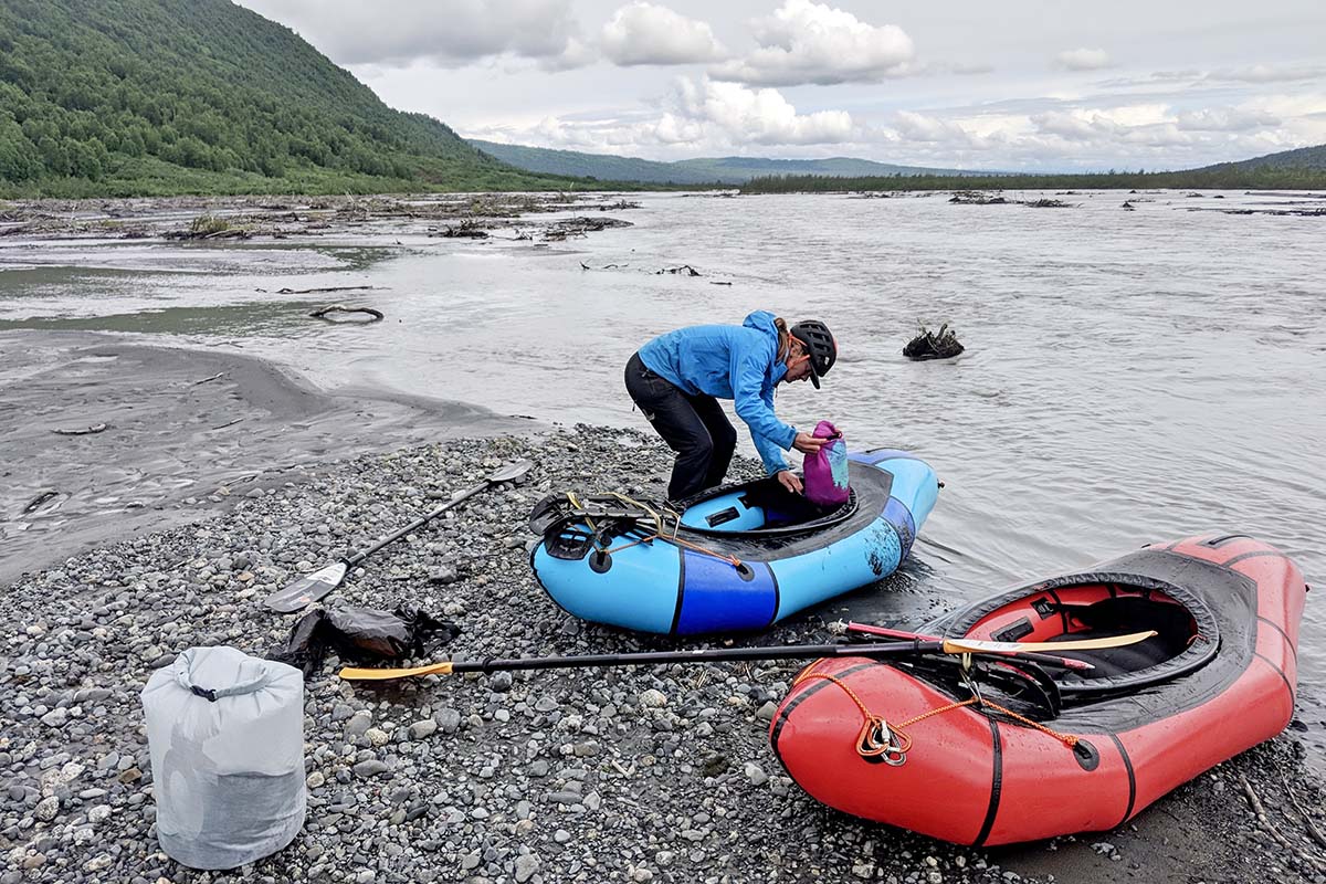 Packing Alpacka Expedition packraft beside river in Alaska