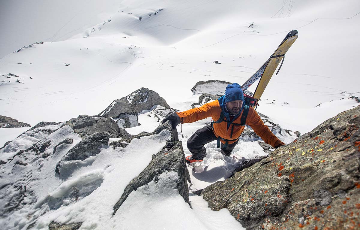 Bootpacking with skis on back wearing baselayer and midlayer