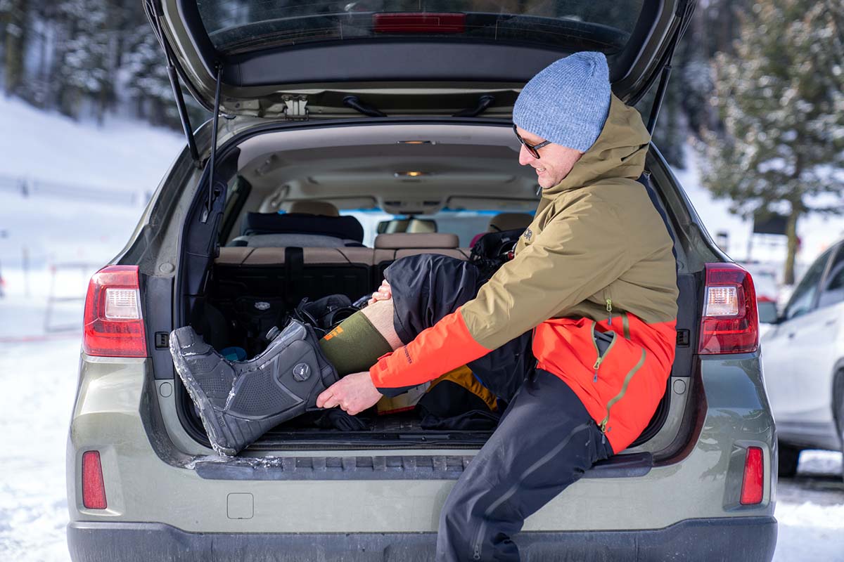 Putting on snowboard boots in rear hatch of car