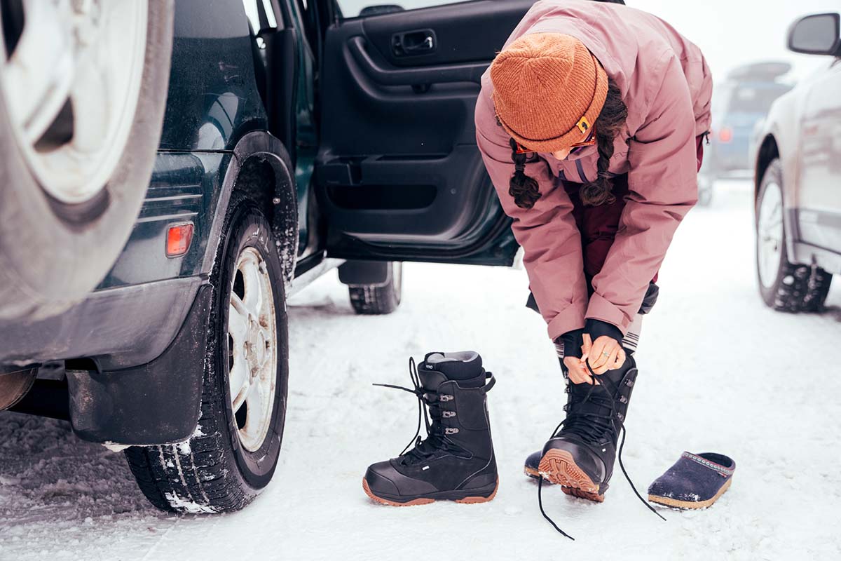 Lacing up snowboard boots in ski area parking lot