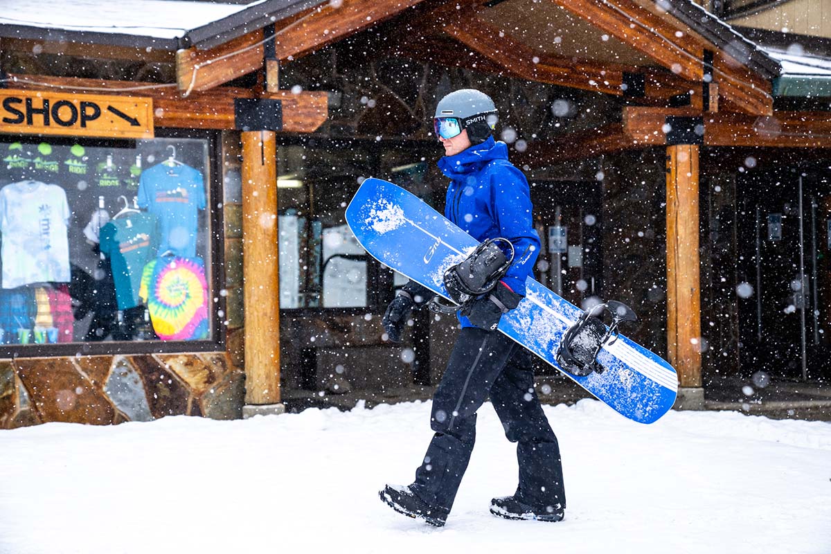 Snowboarding walking in resort carrying board