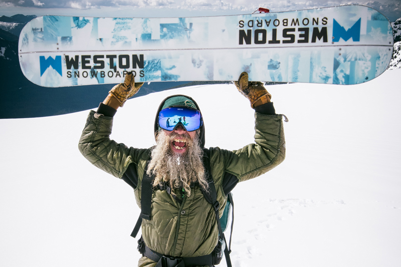 Psyched old school snowboarder holding Weston Splitboard above head