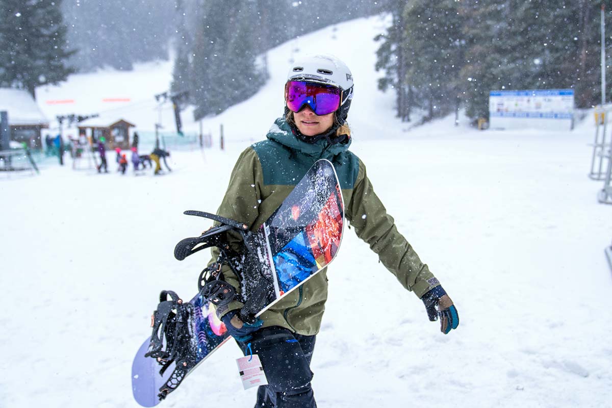 Trew Gear women's snowboard jacket (carrying snowboard near lodge)
