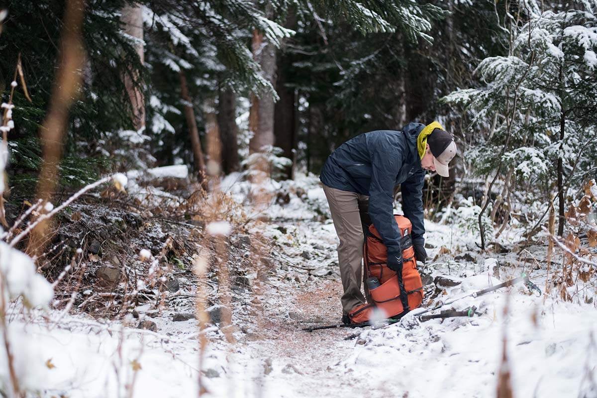 Bending over to pack backpack wearing Arc'teryx Beta AR hardshell jacket