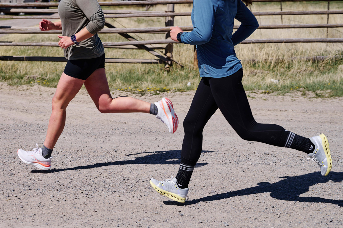 Two women running on a gravel road while wearing fitness watches