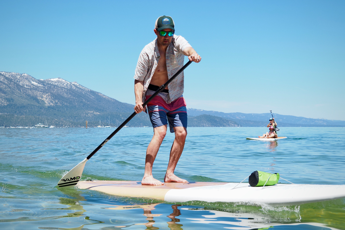 A man paddling fast on Lake Tahoe with the Dax DownDog stand up paddle board