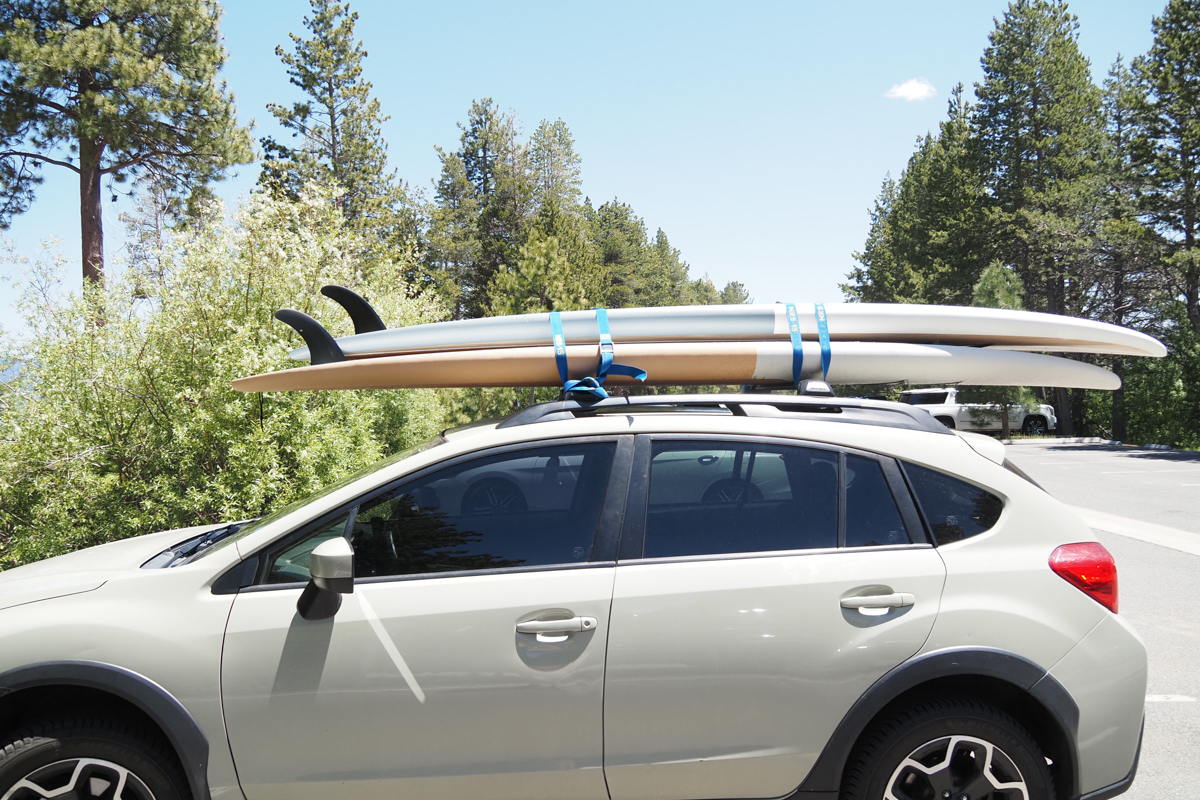 Two stand up paddle boards strapped to the roof rack of a Subaru Crosstrek