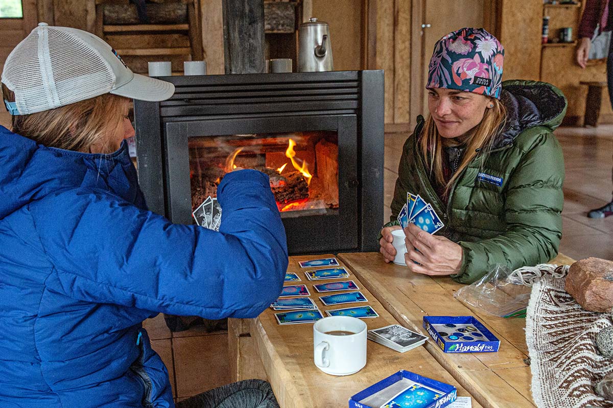 Playing card game in mountain hut (Feathered Friends Eos Down Jacket)