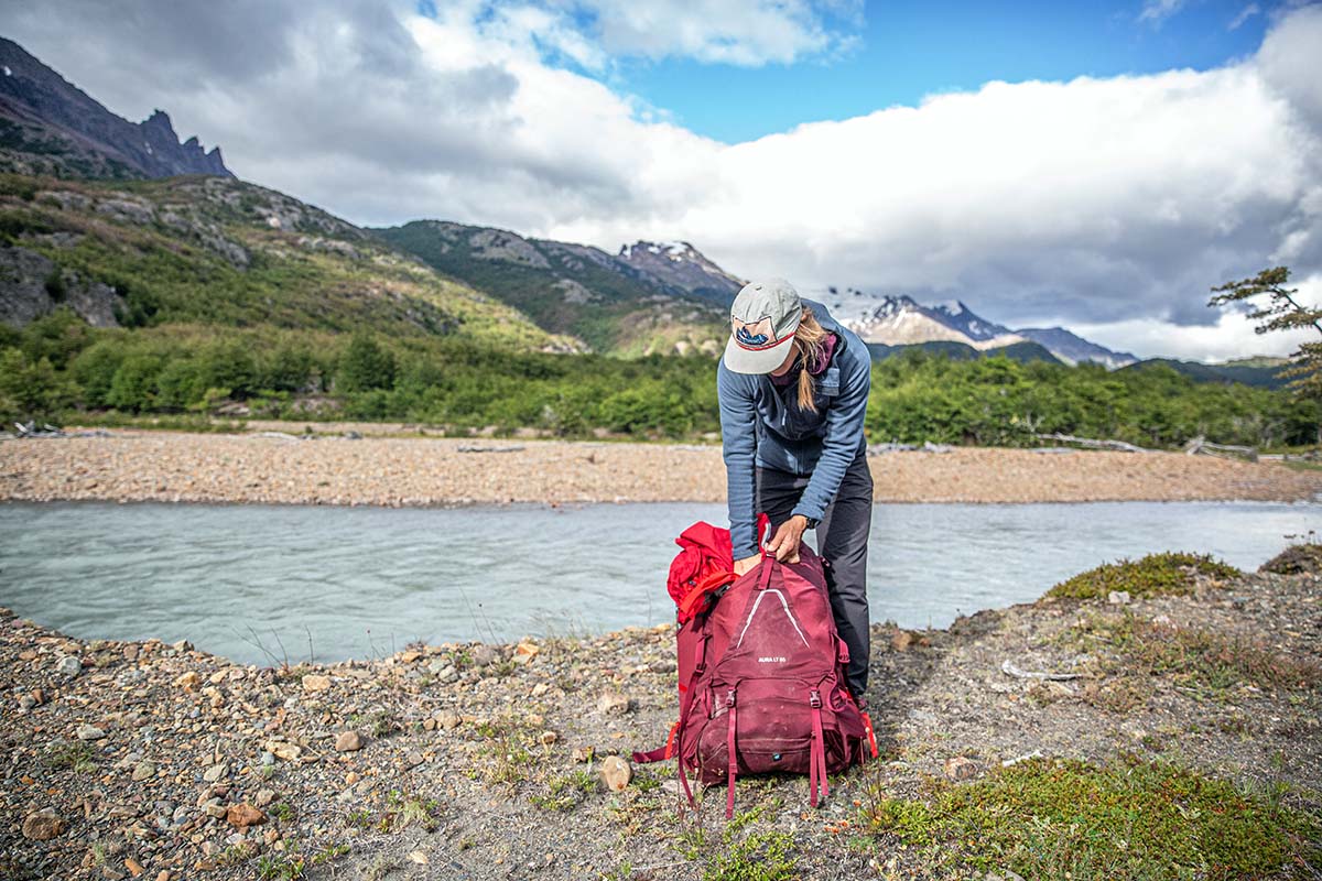 Packing backpack by river (Osprey Aura AG LT 65 women's backpacking pack)