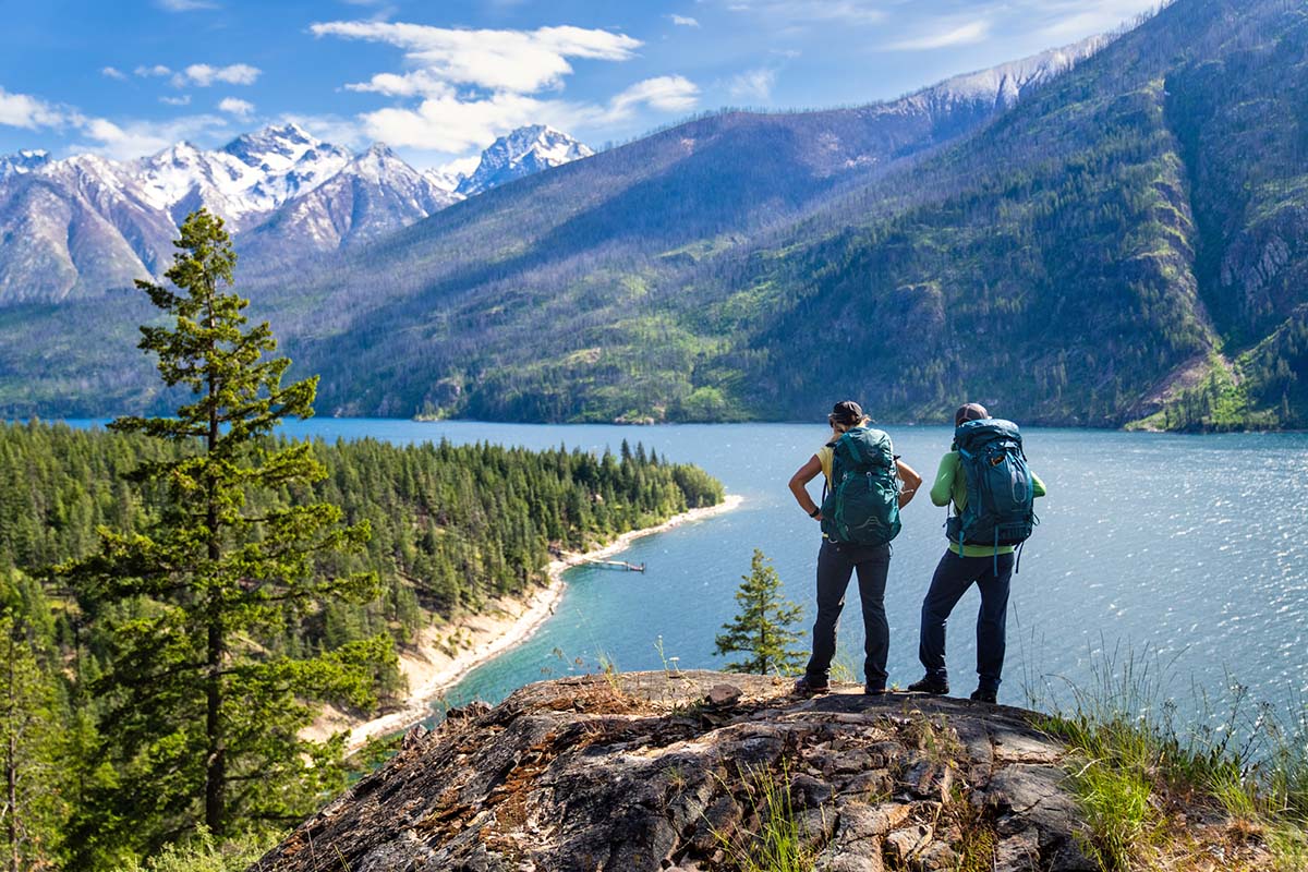 Two hikers staring at mountains over lake (Osprey Eja 58 backpack)