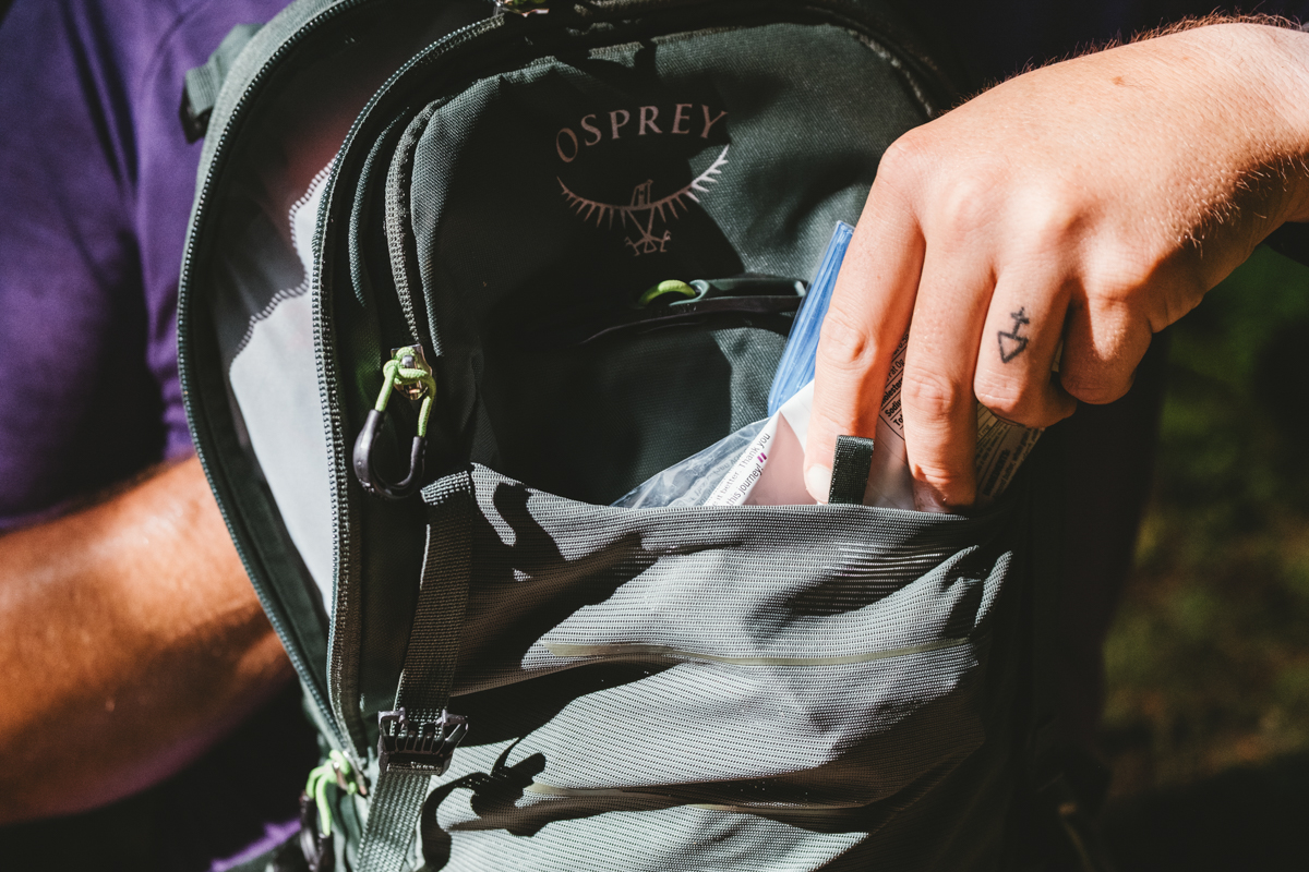 A close up of a hand pulling snacks out of a pocket on a mountain bike backpack