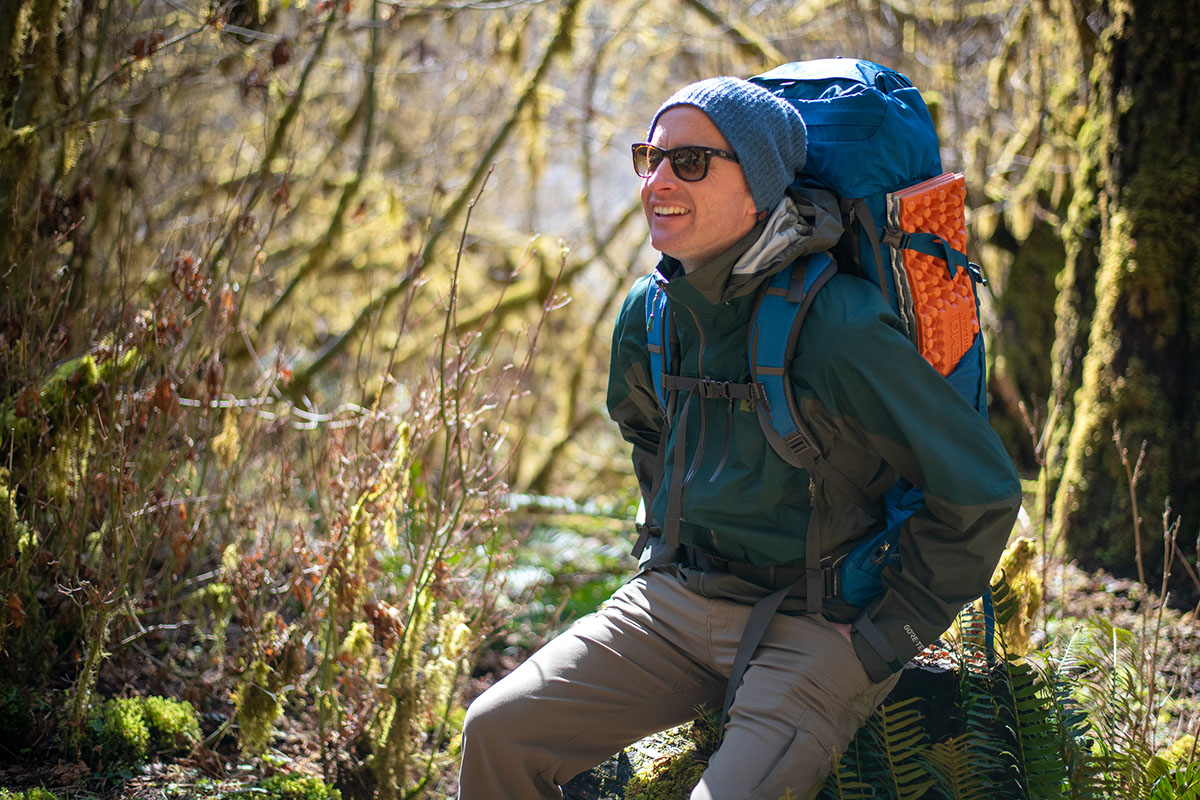 REI Co-op Stormbolt GTX hardshell jacket (sitting on log in forest)