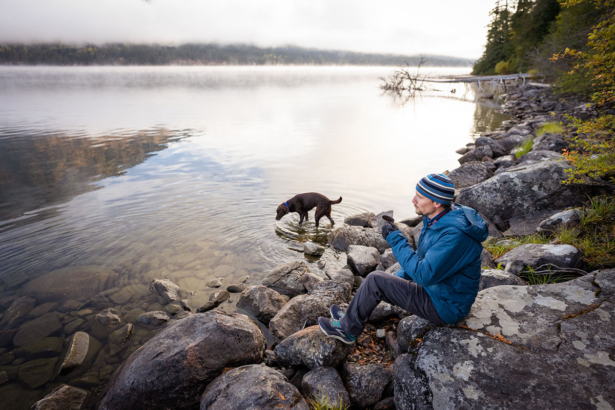 REI Co-op Stormhenge Down Hybrid Jacket (sitting on rocks next to lake)