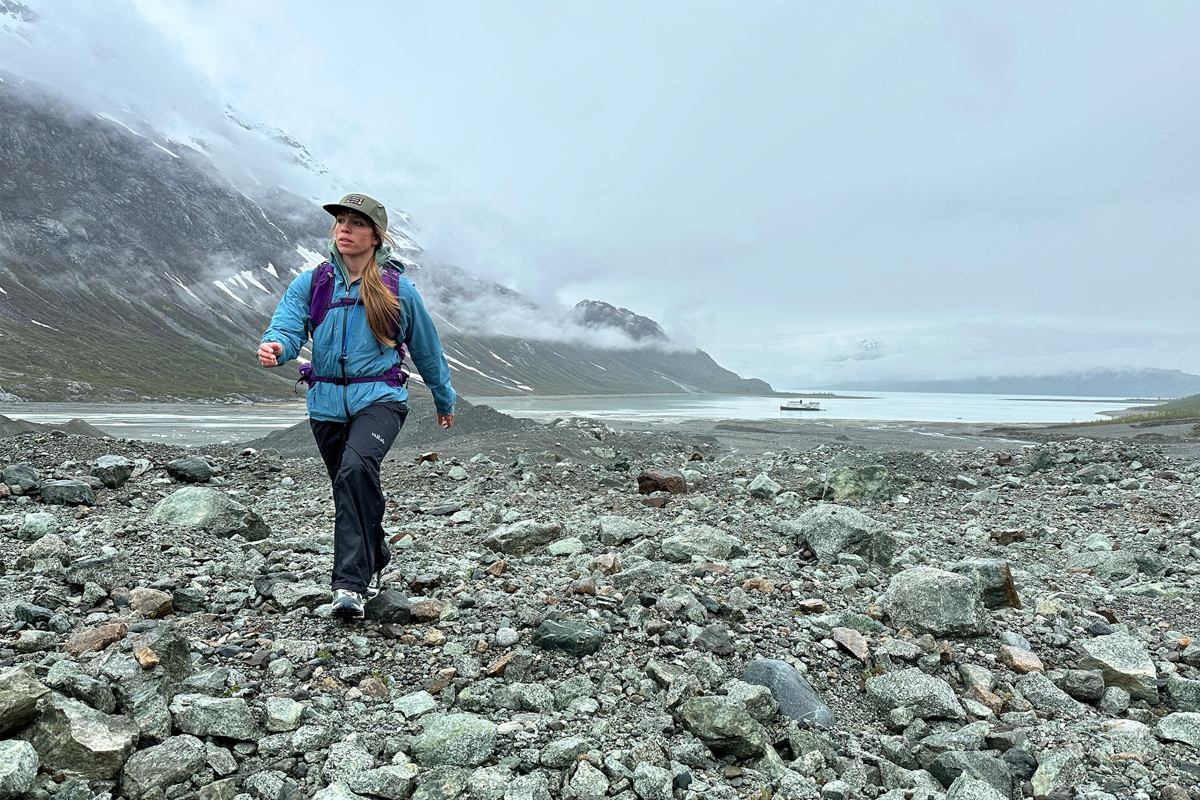 A woman hiking in Salomons shoes on a rocky Alaska coast