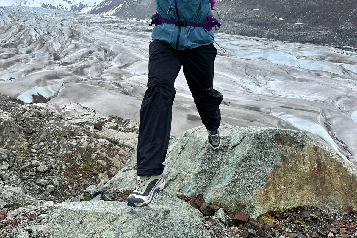 Stepping down onto a boulder in hiking shoes while hiking in a rocky and glaciated landscape