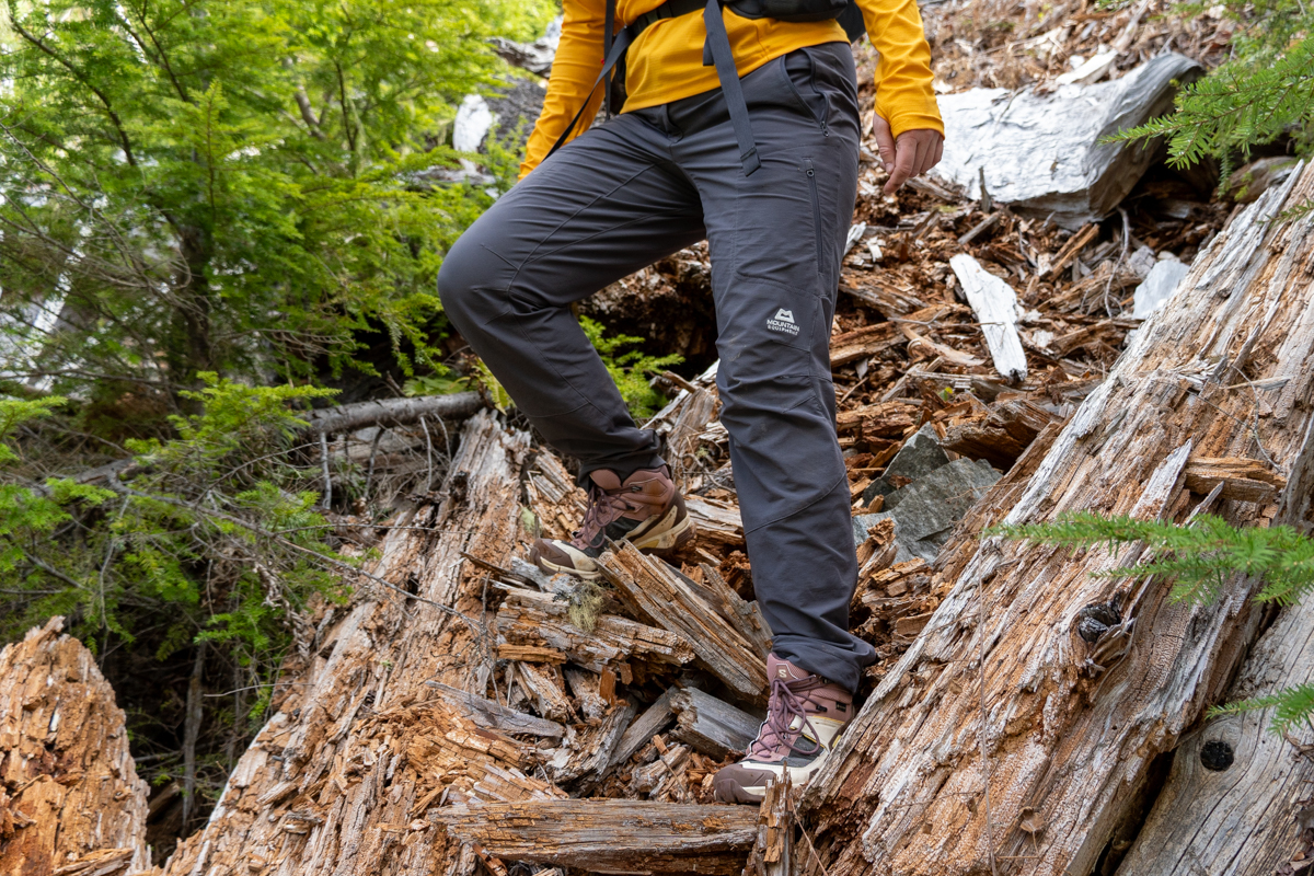 A close up of someone hiking down a steep wooded trail in hiking boots