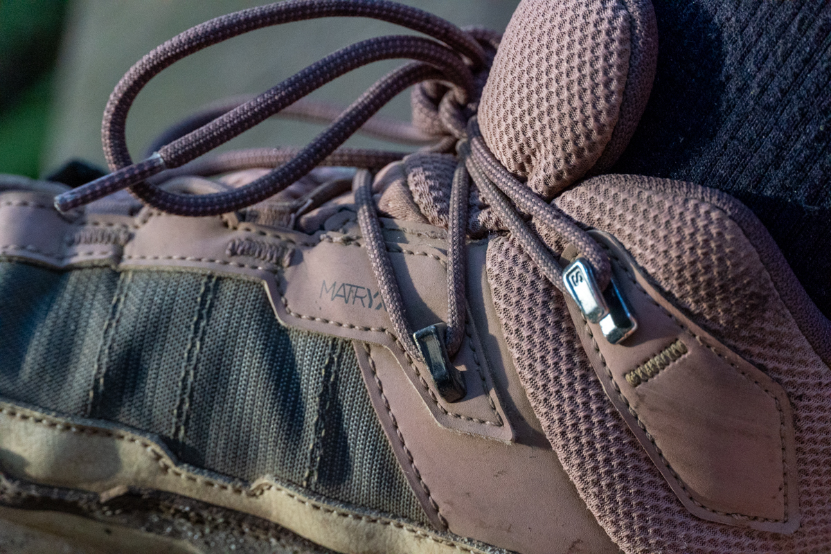A close up of the eyelets on the collar of a brown and pink hiking boot