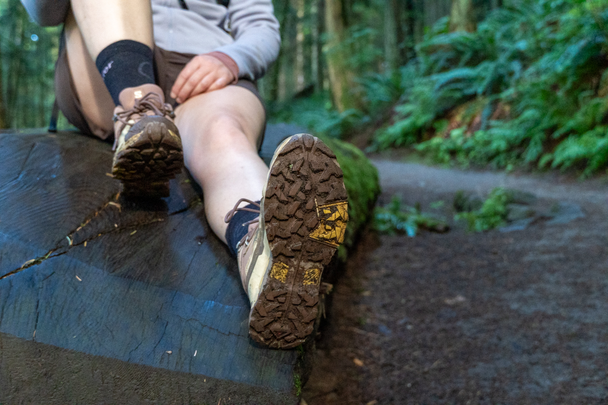A closeup of the tread on the bottom of a hiking boot while boot is propped up on a log
