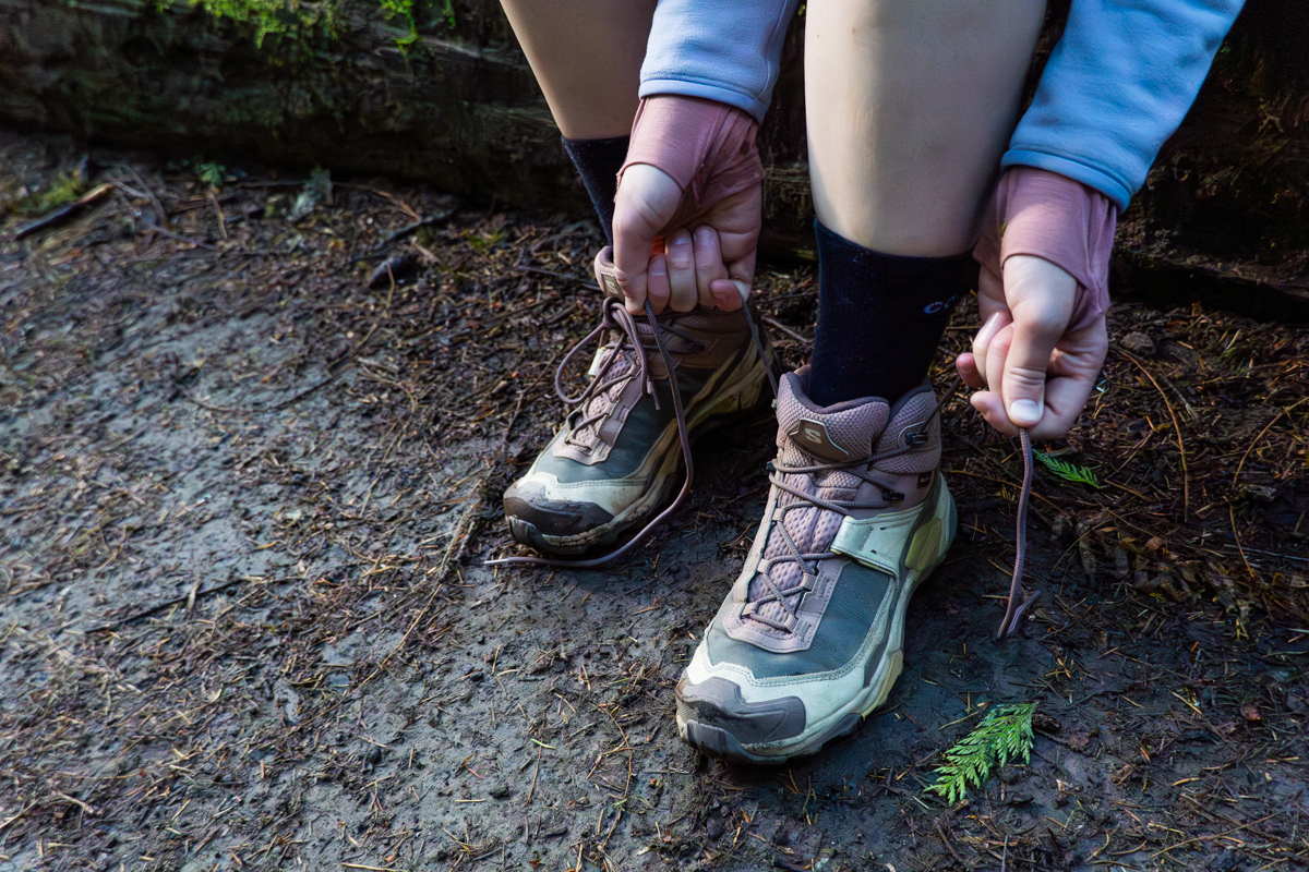 Close up of someone tightening the laces on a pair of brown and pink hiking boots
