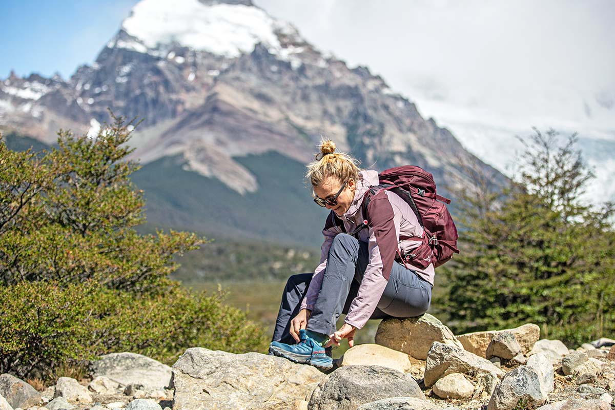 Putting on Scarpa Rush hiking shoes beside trail in Patagonia