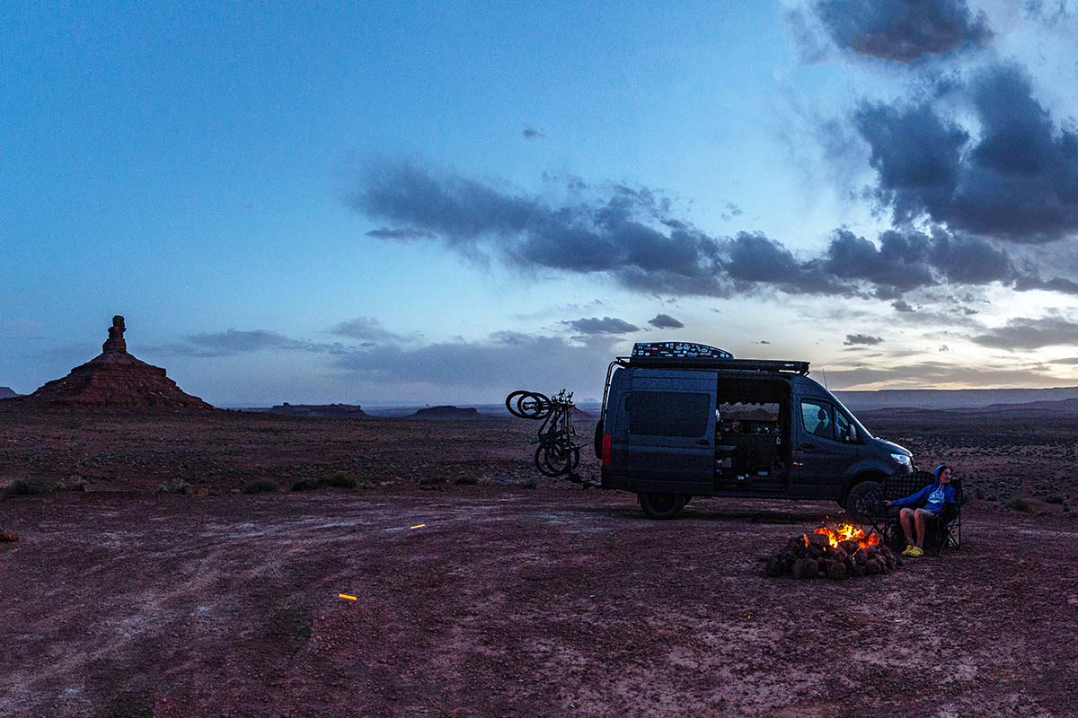 Sitting by campfire and van at desert campsite