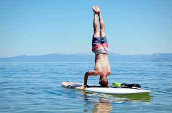 A man performing a head stand on the Dax DownDog stand up paddle board on Lake Tahoe