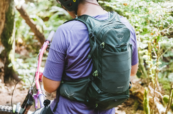 A man wearing a green mountain bike backpack in a forest B