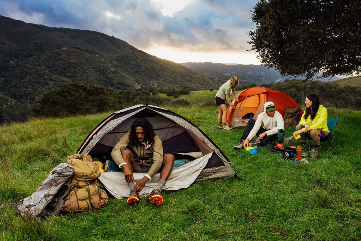 Campers with tents on the grass surrounded with mountains