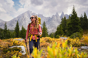 A woman hiking in a field full of autumn colors while wearing a lightweight hoodie.