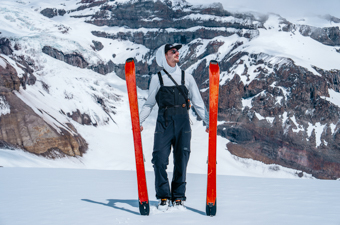 Men's ski bibs (standing with skis in front of glacier)
