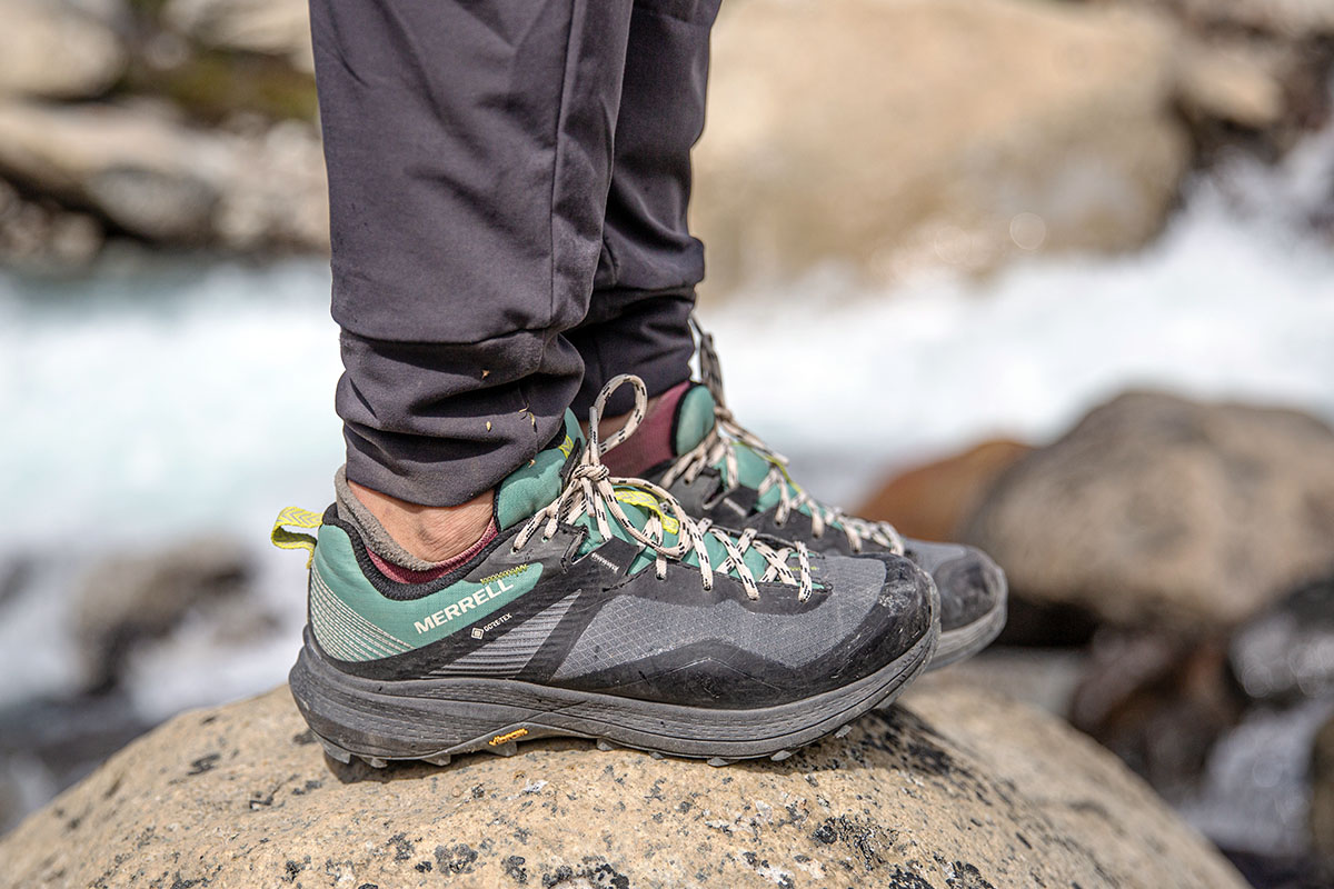 Men's Brown and Gray Merrell Hiking Shoes Holding Stick · Free Stock Photo