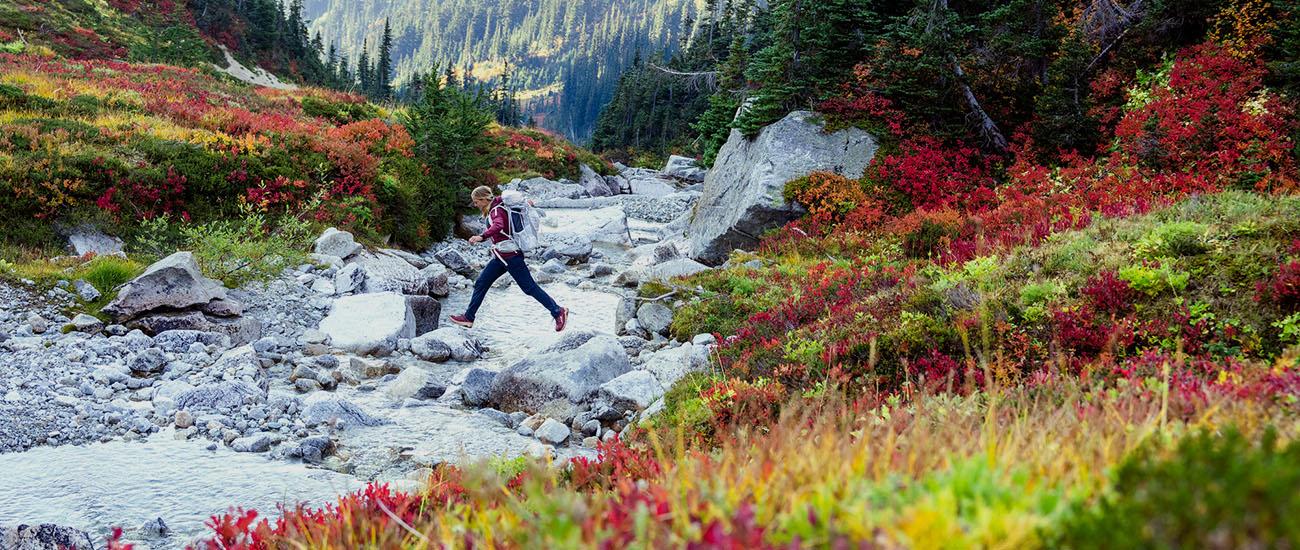 Fall hiking gear essentials (crossing stream with fall colors)