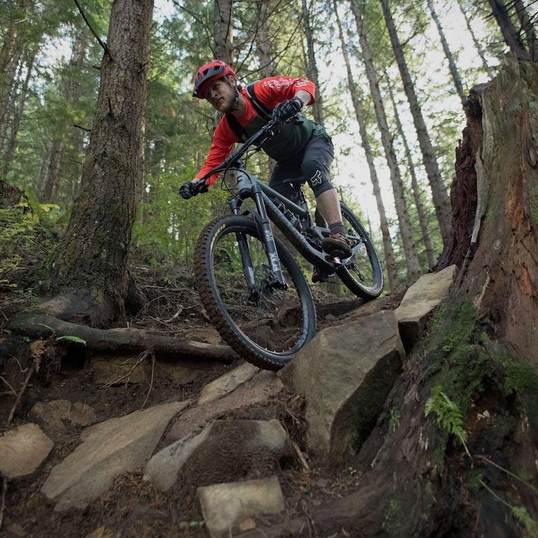 The Santa Cruz Bronson mountain bike coming downhill over some rocks