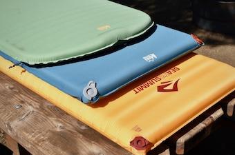 A stack of camping mattresses laid out in the sun