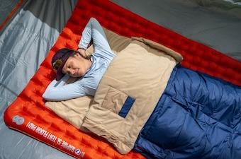 A woman lounges on her back in a tent in the Wawona Bed 20 sleeping bag