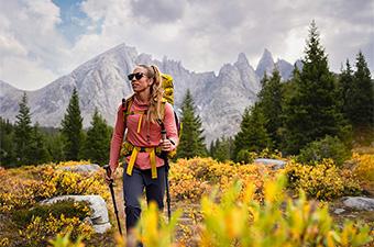 A woman hiking in a field full of autumn colors while wearing a lightweight hoodie.