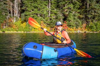 A woman paddles the Alpacka Refuge packraft on a lake in Washington.