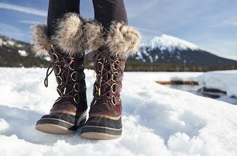 An up close shot of the Sorel Joan of Arctic with a lake and snow in the background.
